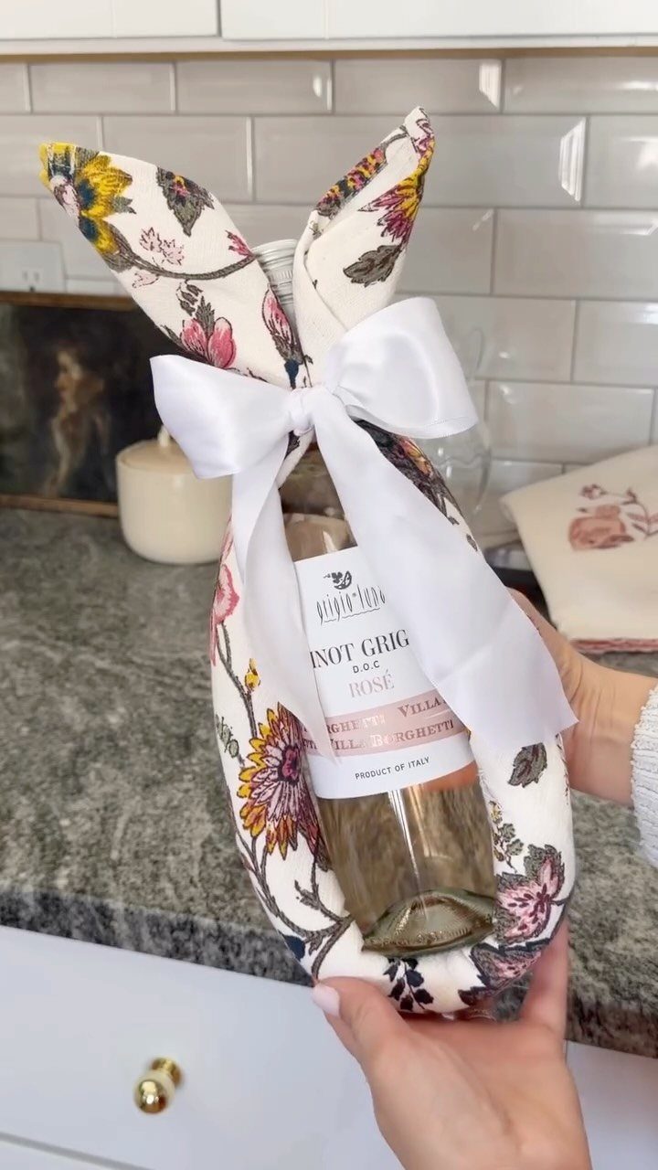 Wine bottle wrapped in floral fabric to look like a bunny with white bow.