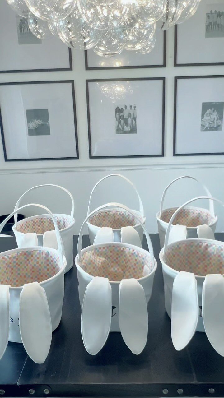 White fabric Easter baskets with bunny ears arranged on a dark table.