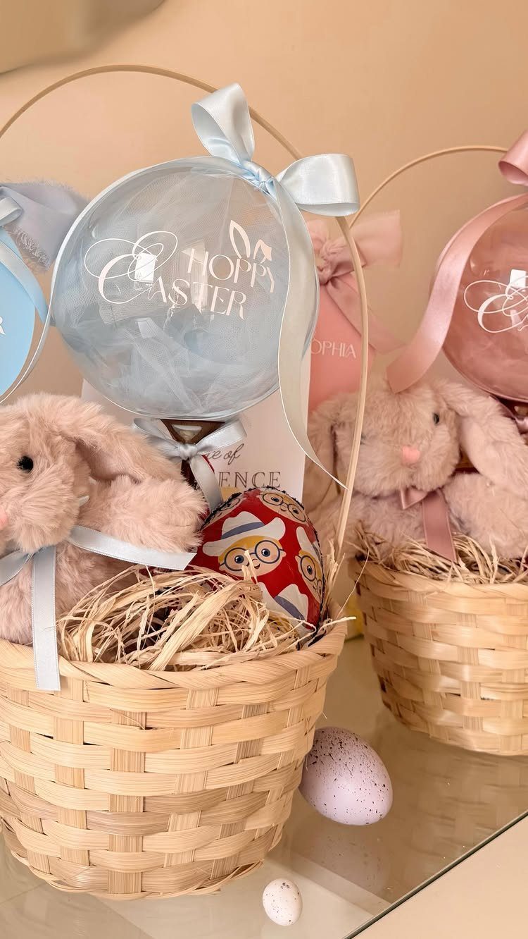 Woven Easter baskets with plush bunnies, decorated eggs, and large pastel balloons.
