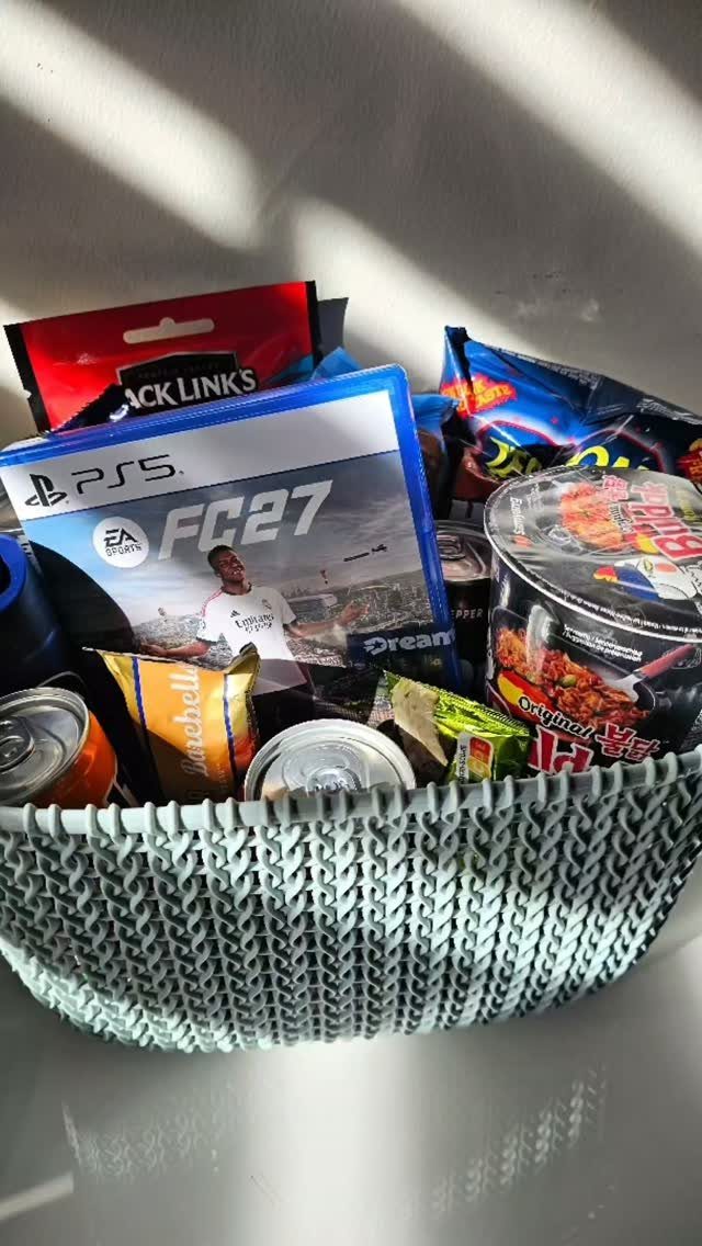 Light blue woven basket filled with PS5 game, snacks, and canned drinks.