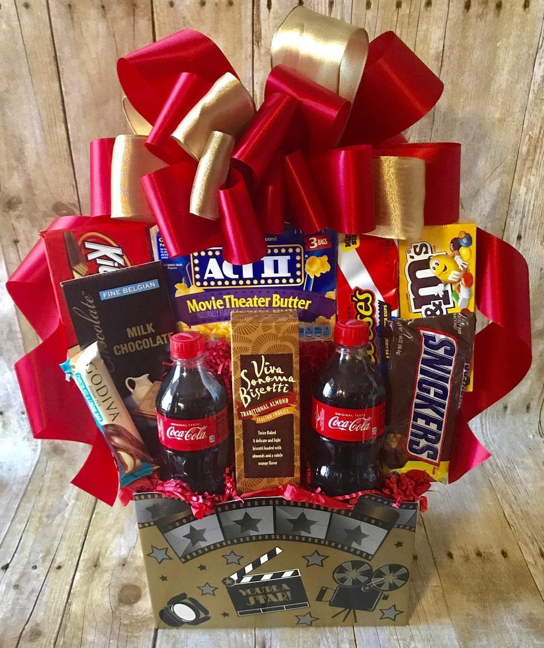 Movie snack gift basket with popcorn, soda, and candy topped with a red bow.