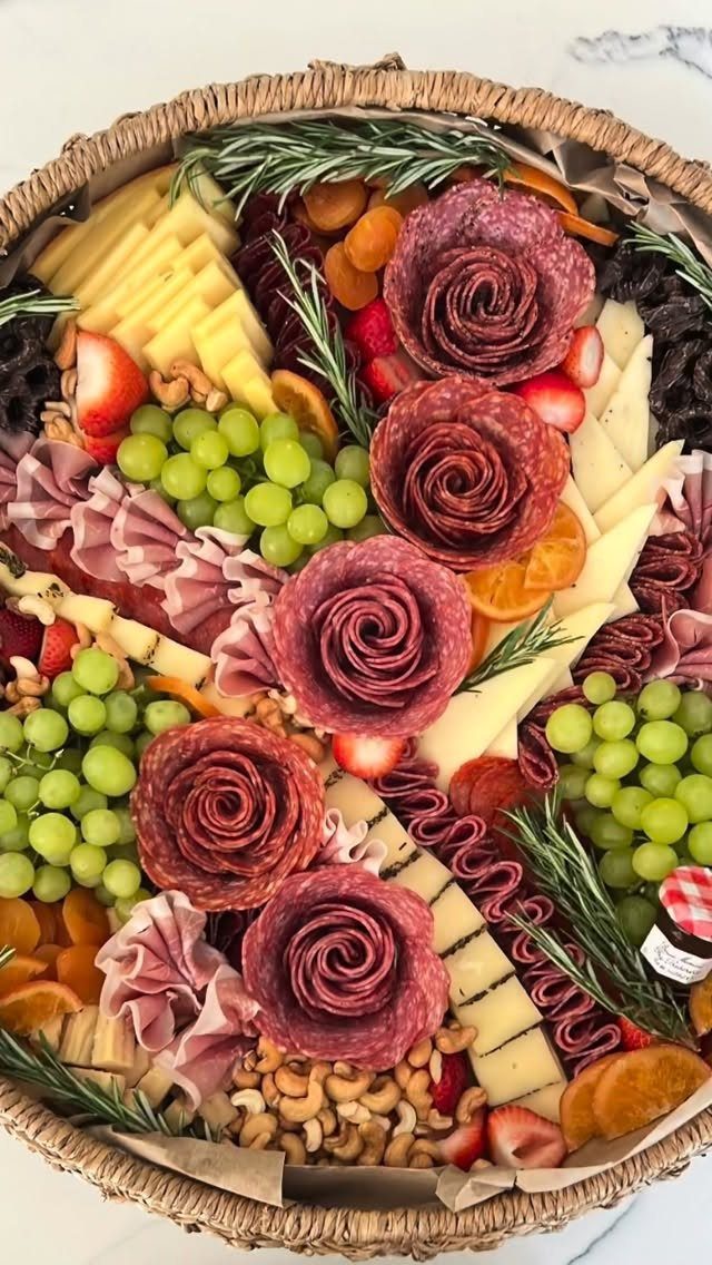 Charcuterie basket with gourmet cheeses, salami roses, green grapes, and dried fruits.