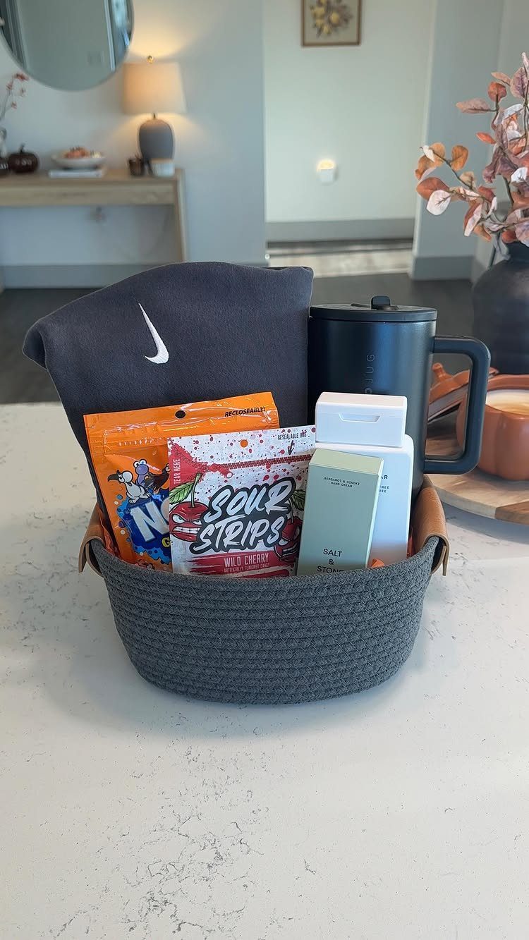 Grey woven gift basket filled with a Nike shirt, travel mug, and candies.