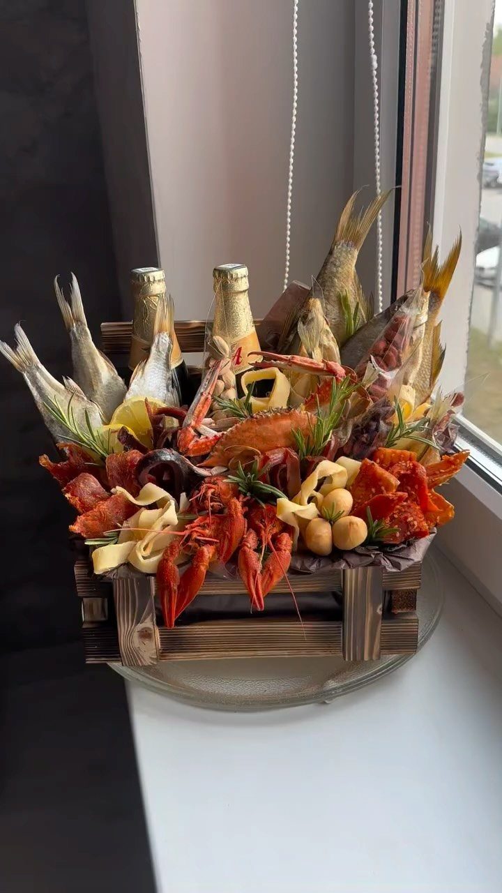 Wooden crate filled with dried fish, seafood snacks, and two glass bottles.