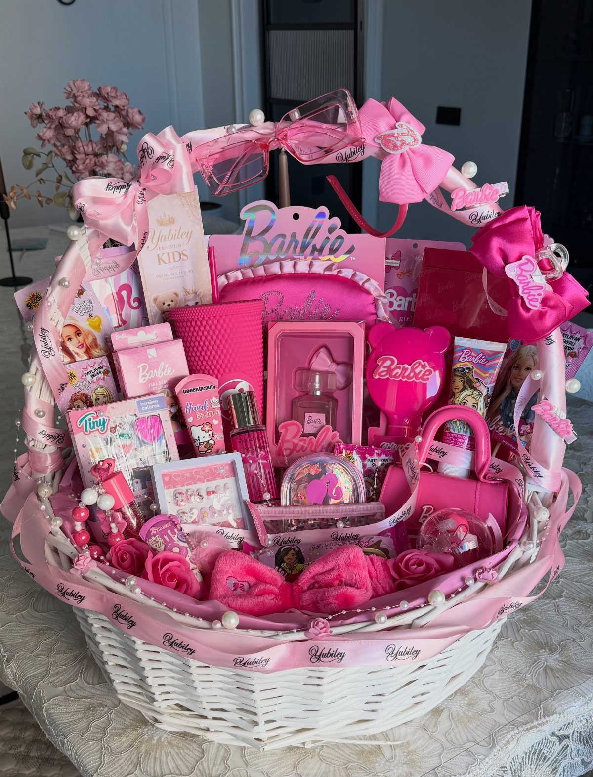 White wicker basket filled with pink Barbie toys and accessories for a child.