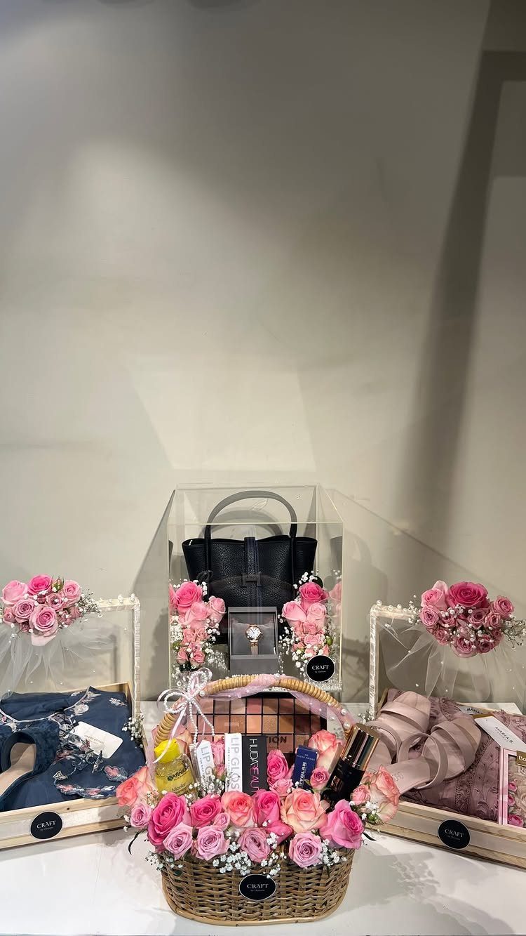 Luxury gift basket with pink roses, perfumes, and high-end accessories in acrylic boxes.