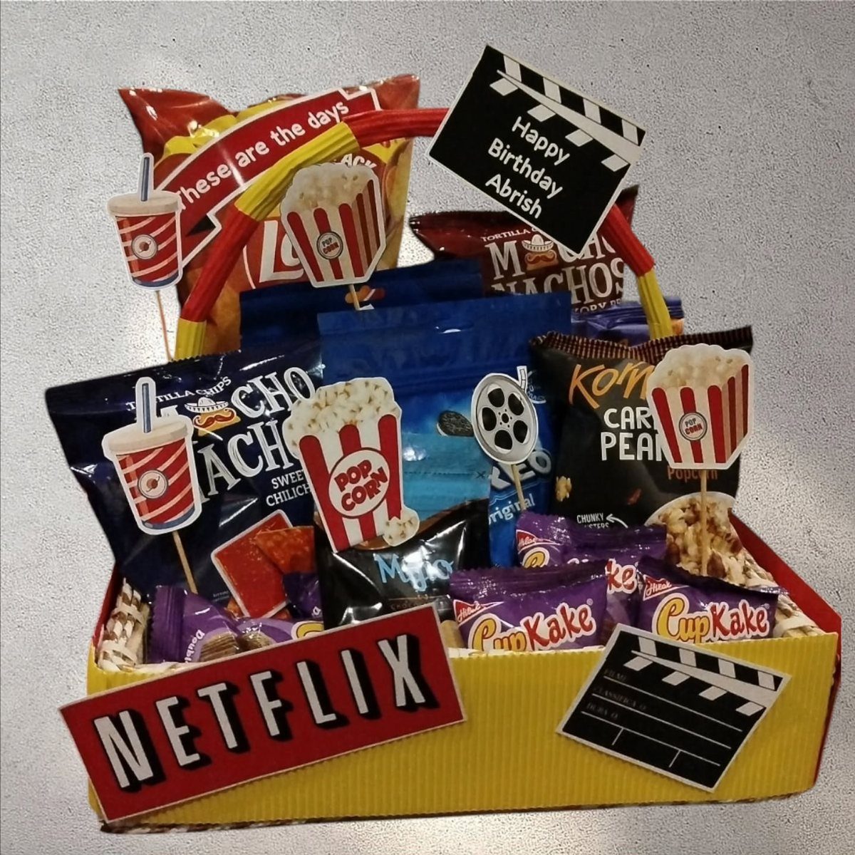 Movie night birthday basket with snacks, Netflix sign, and cinema-themed decorations.