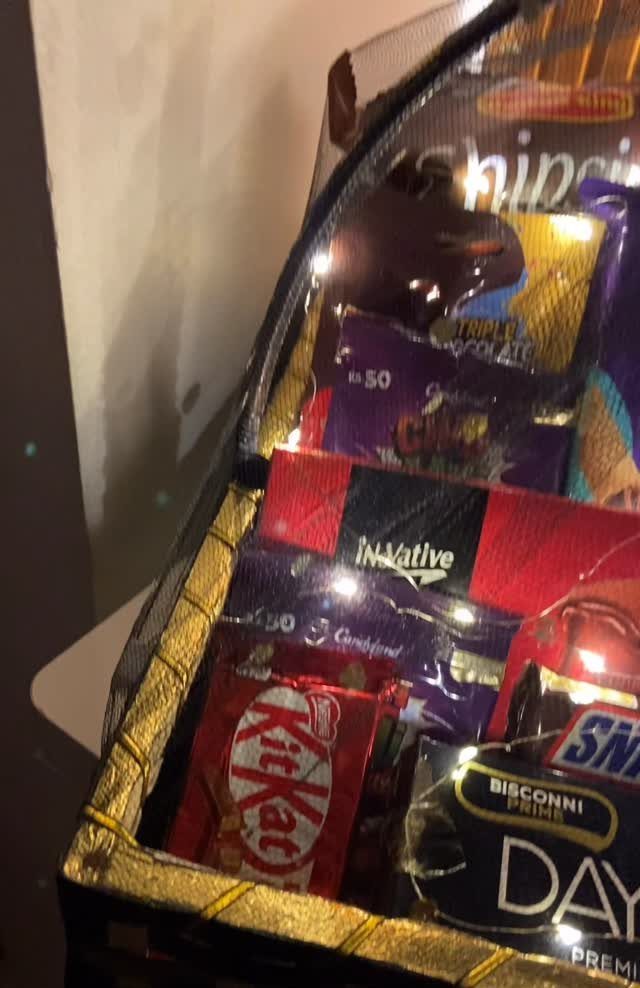 Gift basket filled with assorted chocolates and snacks wrapped in clear cellophane.