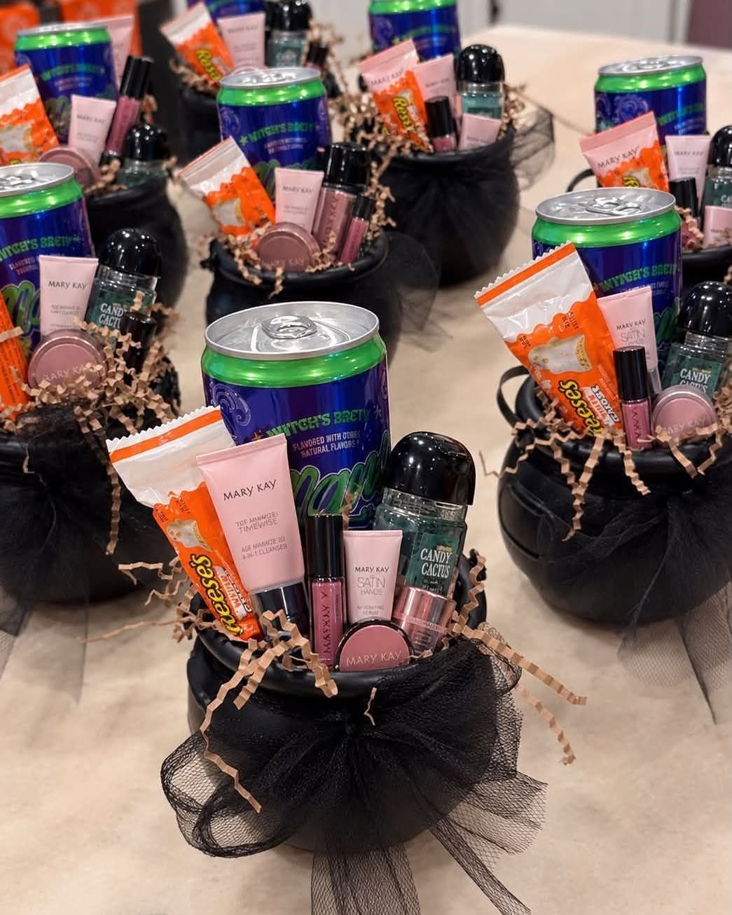Black cauldron baskets filled with Halloween treats, makeup, and green cans with tulle bows.