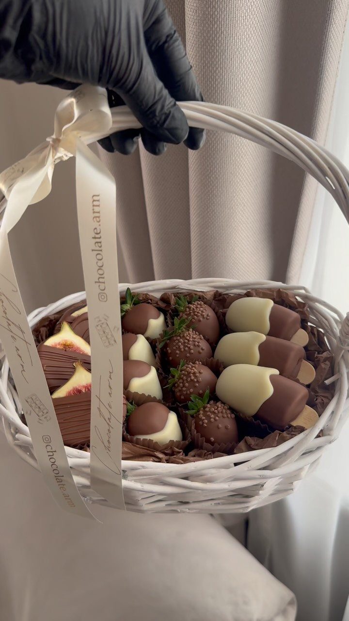 White wicker basket filled with chocolate covered strawberries and gourmet chocolate treats.