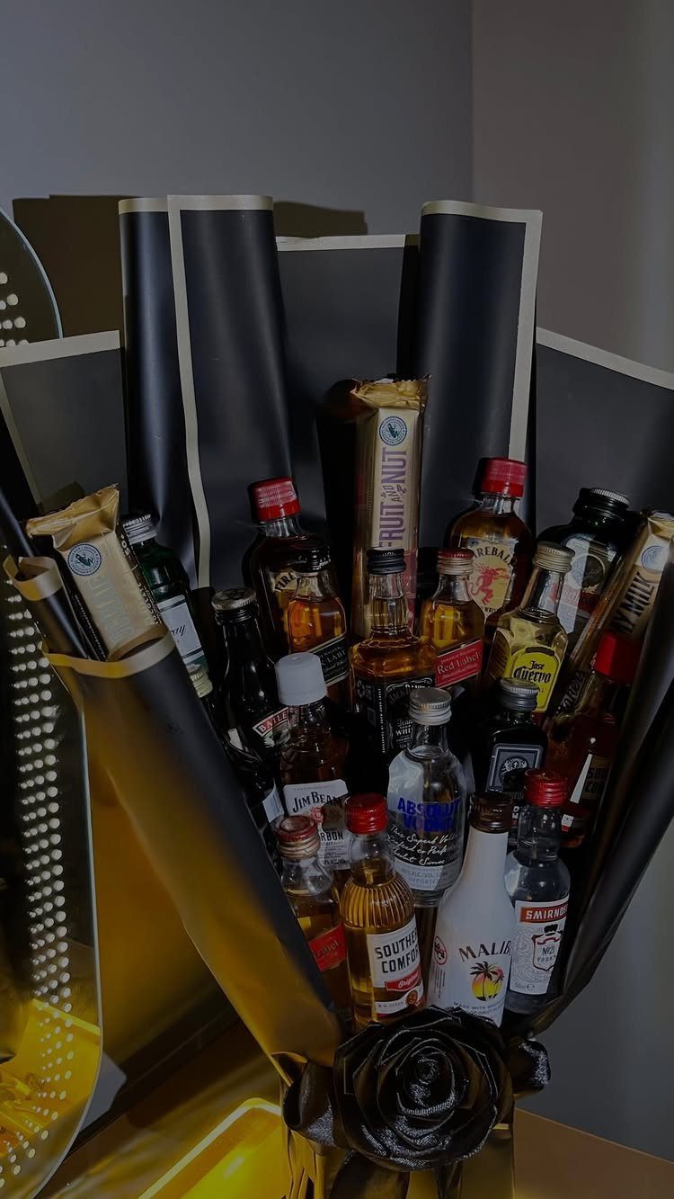 Miniature liquor bottles arranged in a black and gold decorative gift bouquet.