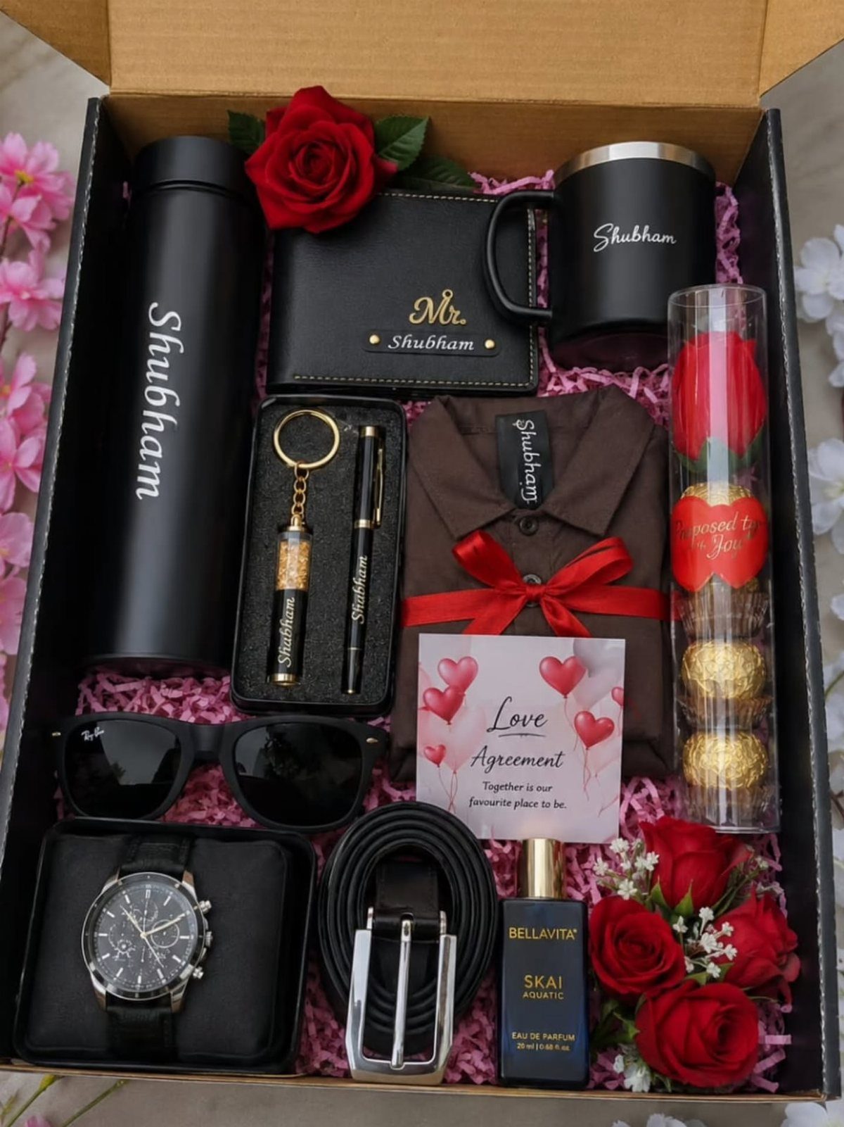 Personalized gift box for men with black accessories, red roses, and a red ribbon.