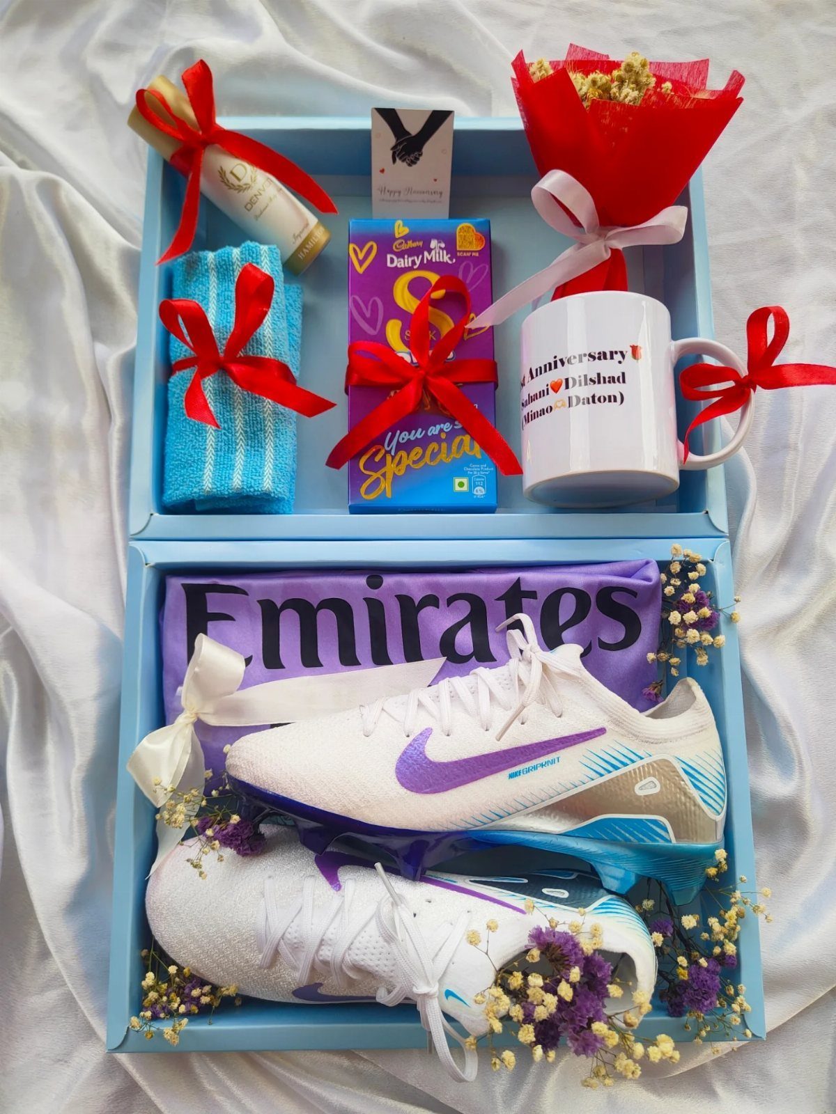 Gift box with white soccer cleats, purple jersey, chocolate, and a red bouquet.