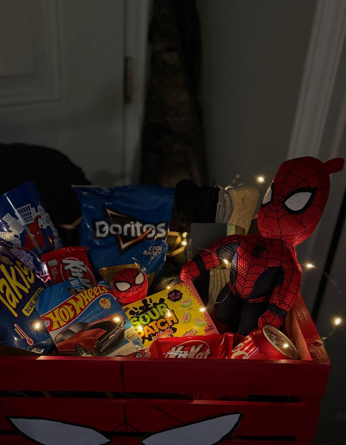 Spider-Man themed gift crate filled with various snacks and a plush toy.