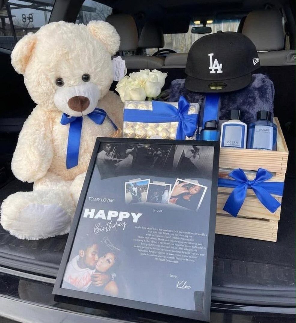 Gift arrangement with teddy bear, wooden crate, and framed birthday message in car trunk