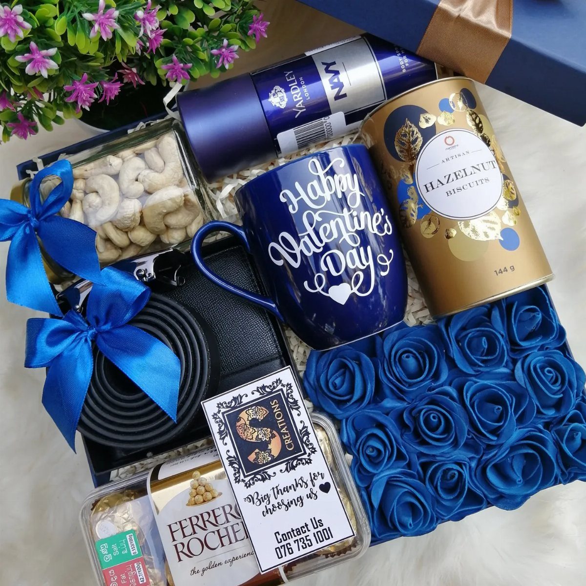 Valentine's Day gift basket with blue mug, blue roses, and various treats.