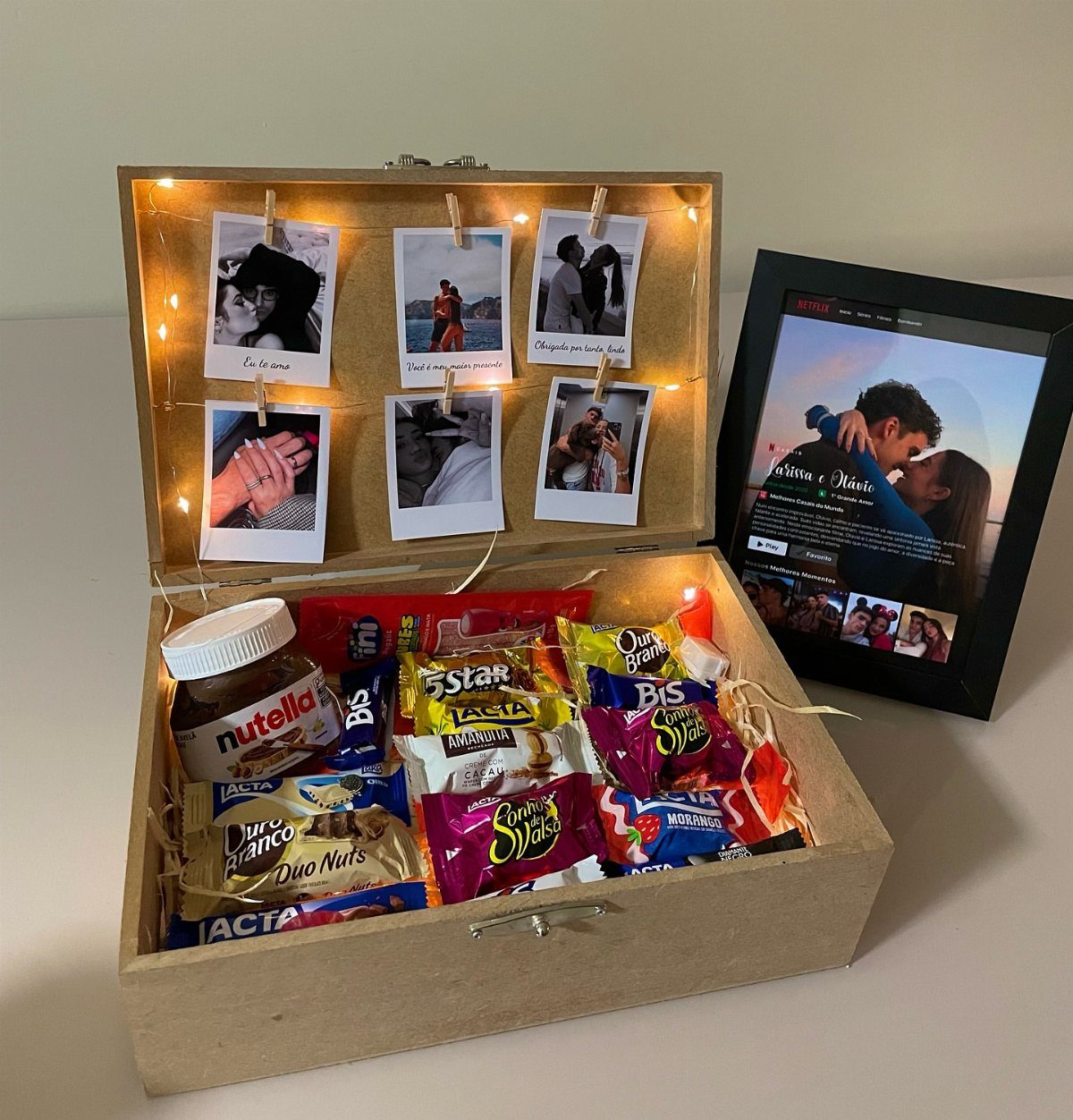 Wooden gift box filled with sweets and polaroid photos with fairy lights