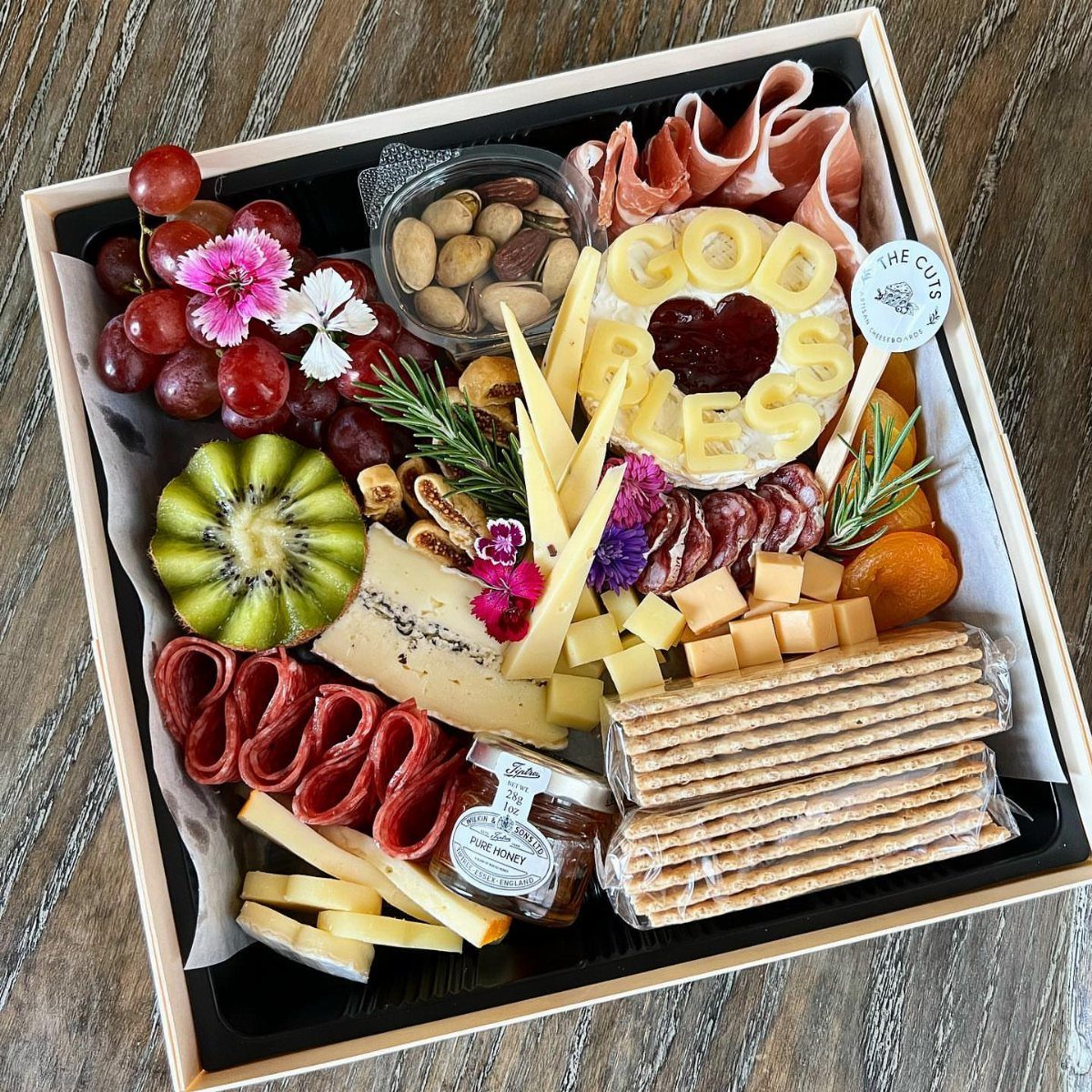 Charcuterie gift box with meats, cheeses, fruits, and crackers for Valentine's Day.