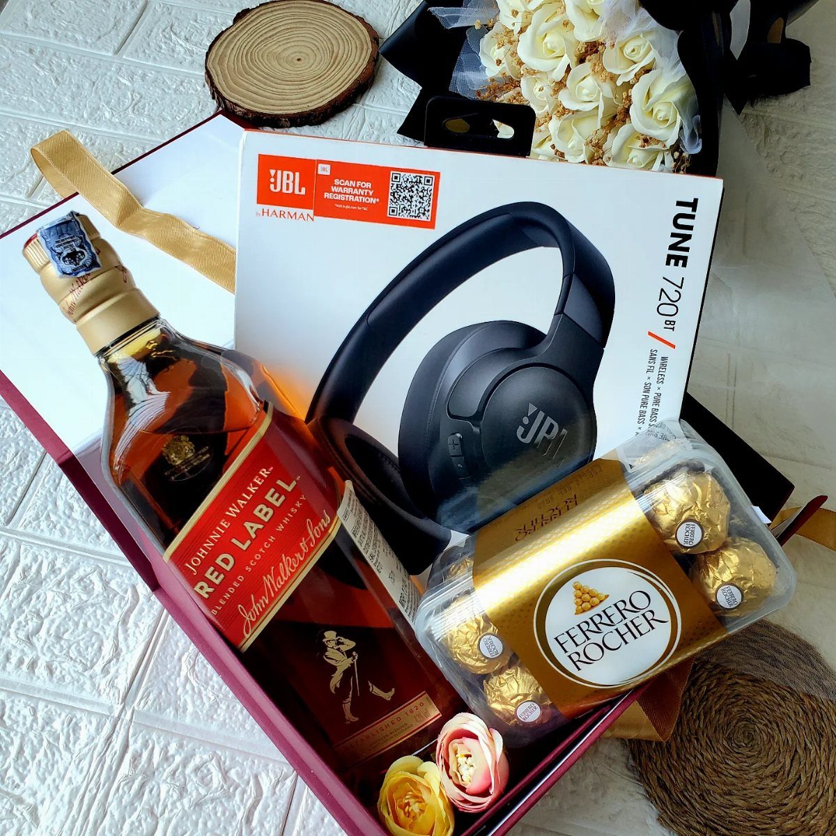 Whiskey bottle, JBL headphones, and Ferrero Rocher chocolates in a red gift box.