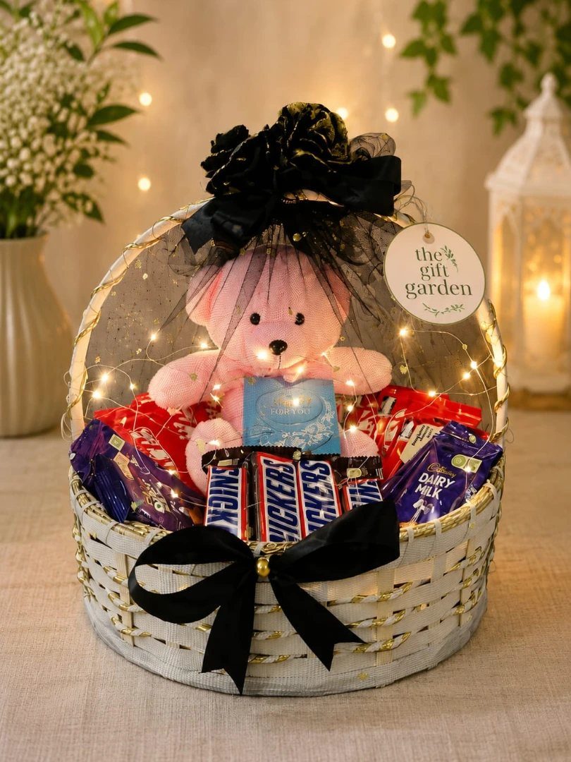 Gift basket with pink teddy bear and chocolates wrapped in glowing fairy lights