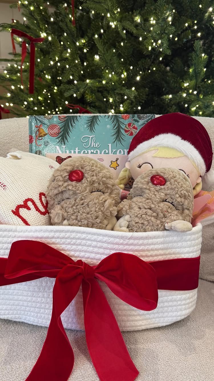 White woven gift basket with red bow containing plush toys and Nutcracker book.