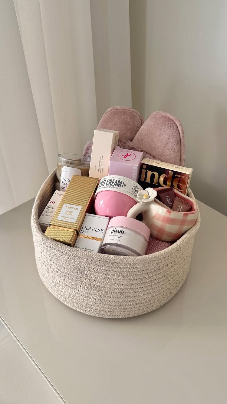 Woven burr basket filled with pink beauty products and fluffy slippers as a gift.