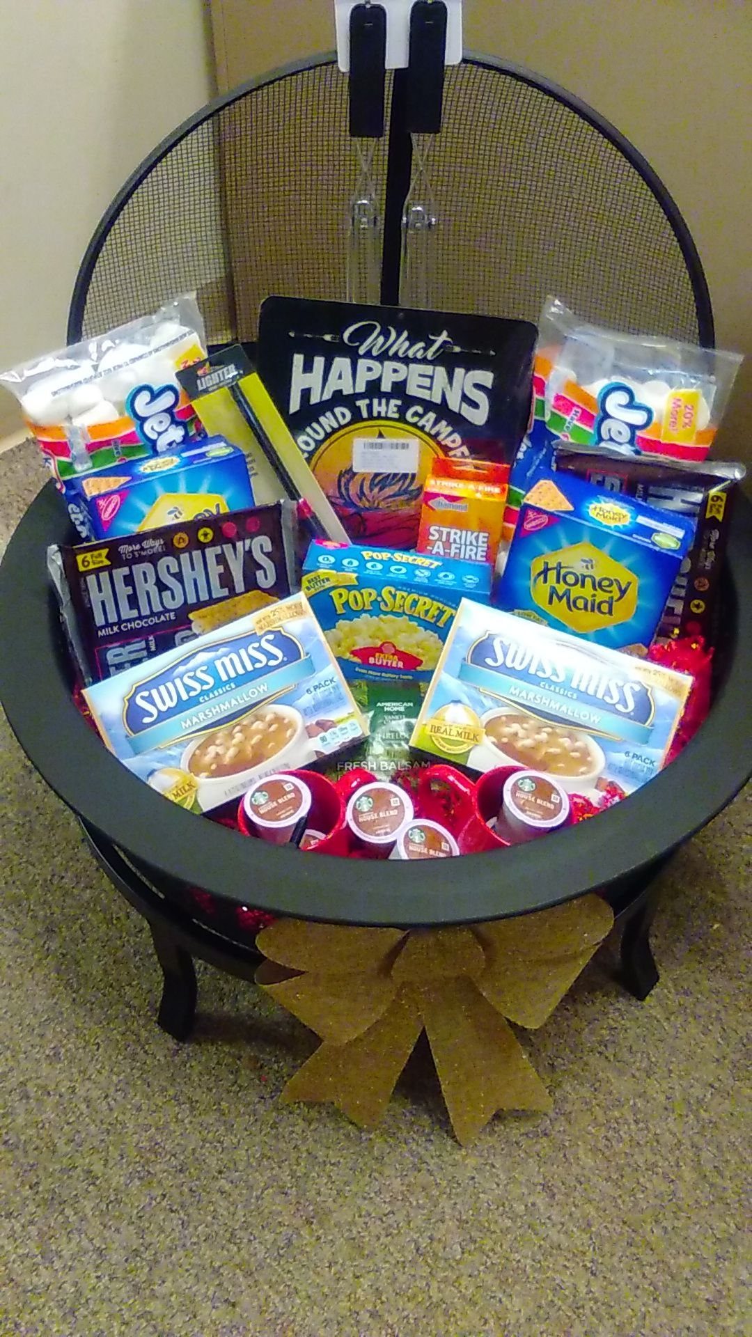 Camping snack gift set inside a black metal fire pit with a brown bow.