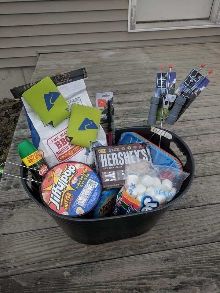 Black tub filled with s'mores ingredients and camping gear on a wooden deck.