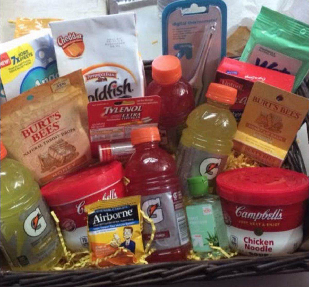 Wicker care basket filled with soup, sports drinks, medicine, and snacks for recovery.