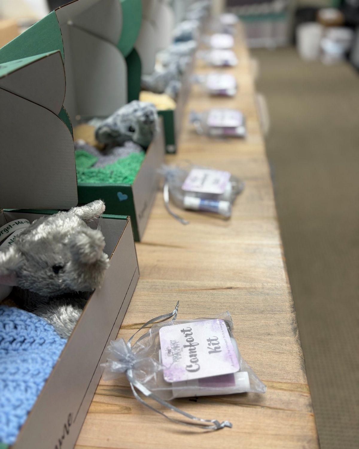 Comfort kits with plush animals in boxes and small gift bags on a table.