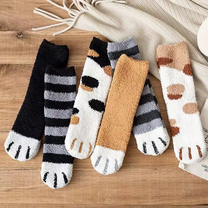 Fuzzy socks in various colors and animal patterns on a wooden surface.