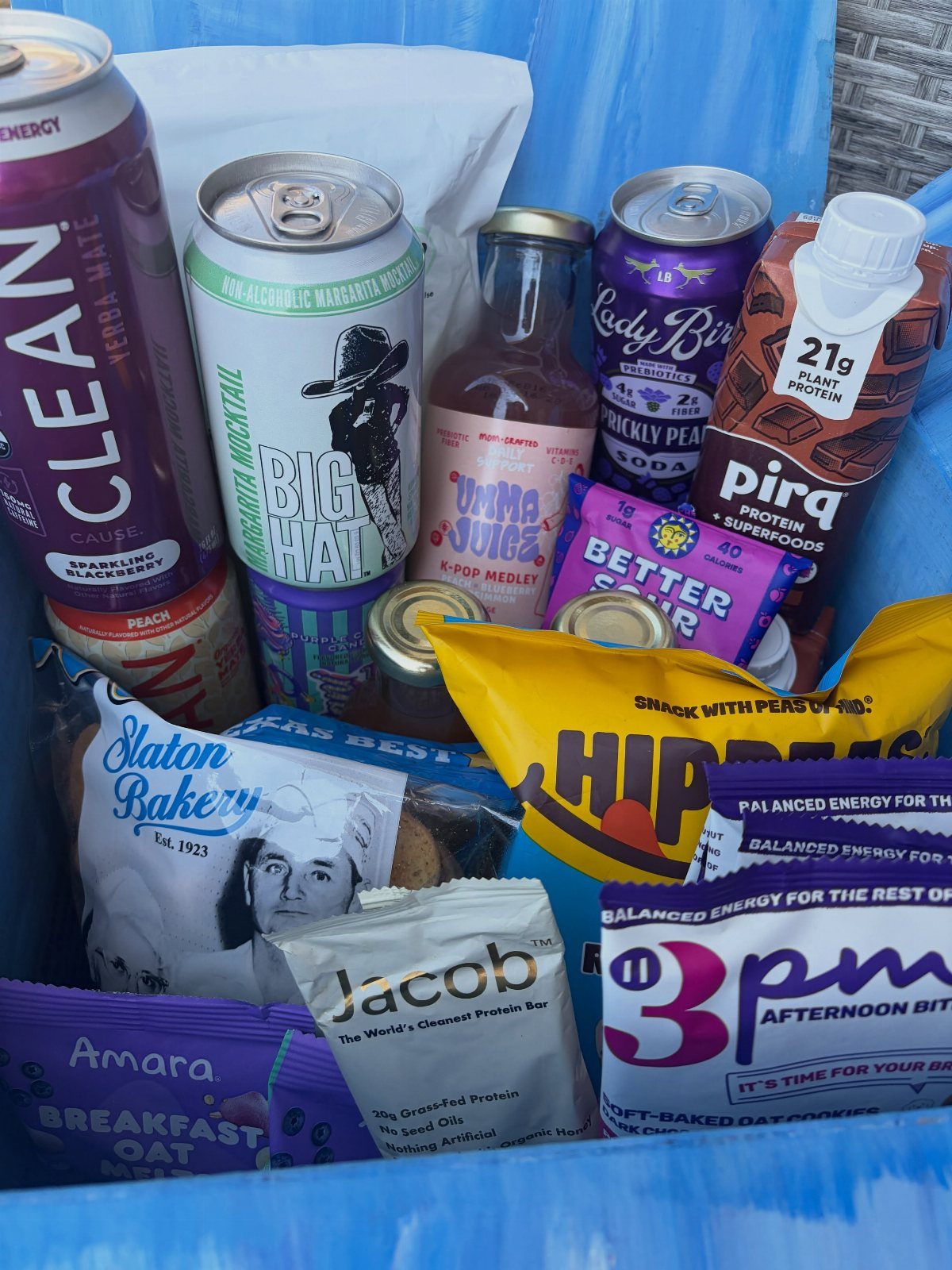 Assorted snacks and functional beverages packed inside a bright blue storage bin.