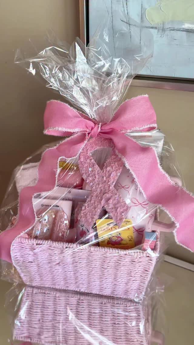 Pink gift basket wrapped in cellophane with a pink bow and awareness ribbon.