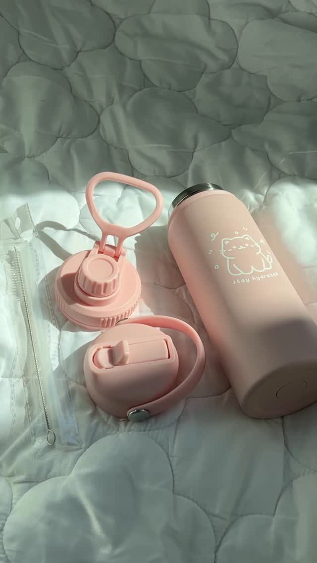Pink water bottle and earbud case on a white quilted blanket.