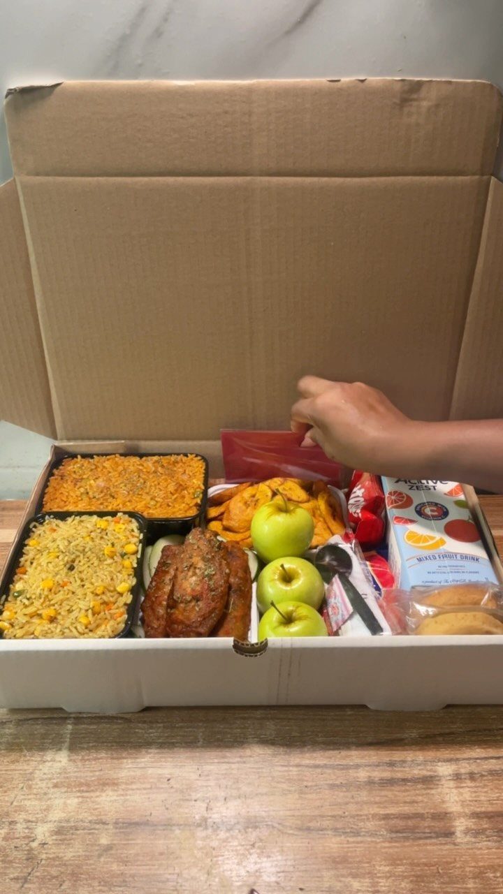 Open delivery box filled with cooked meals, green apples, and a drink carton.