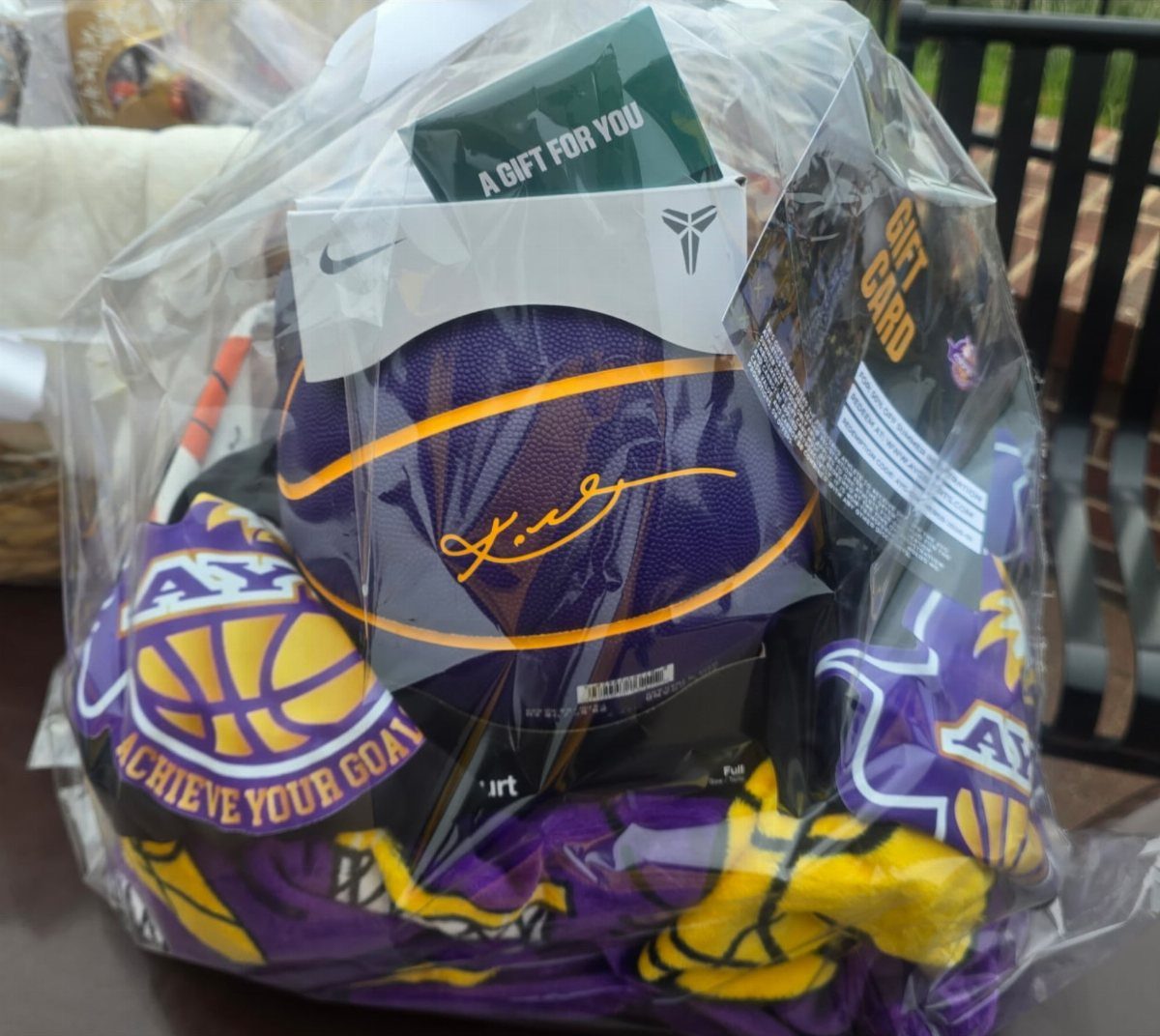 Sports themed gift basket with a purple basketball and apparel wrapped in cellophane