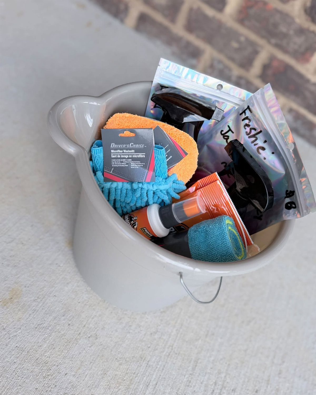 Car cleaning supplies including sponges and duster in a grey ceramic pot.