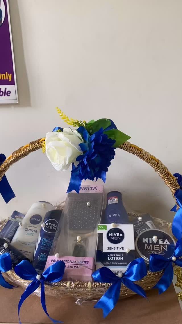 Wicker gift basket filled with men's grooming products and decorated with blue ribbons.