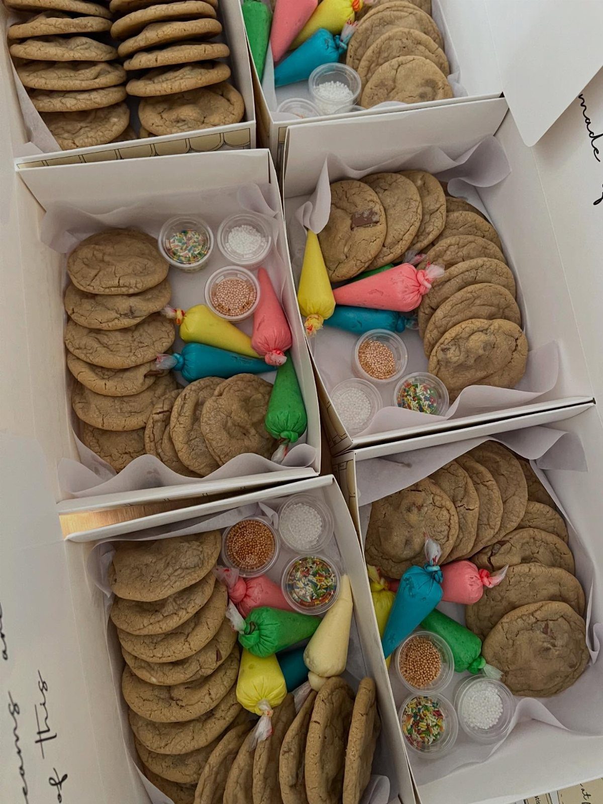 Cookie decorating kits in white boxes with plain cookies, frosting, and sprinkles.