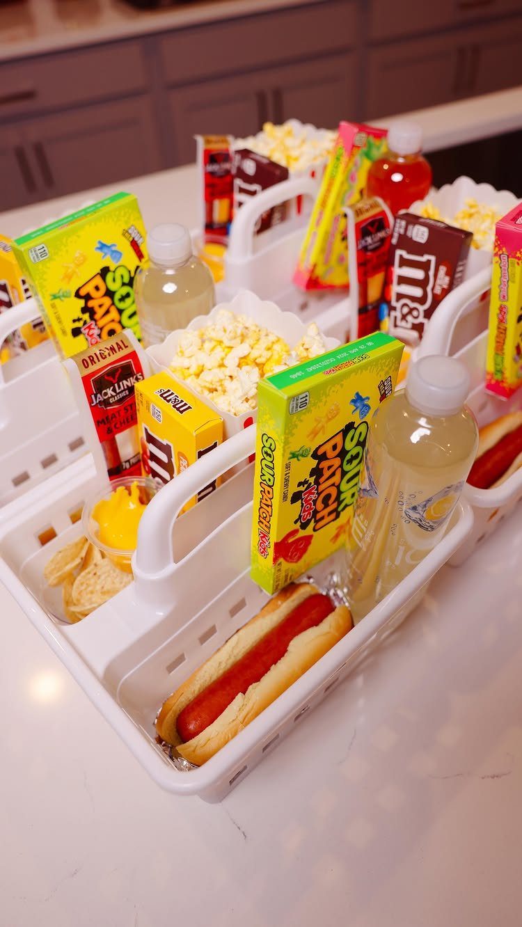 Movie snack baskets containing candy, popcorn, and hot dogs on a white counter
