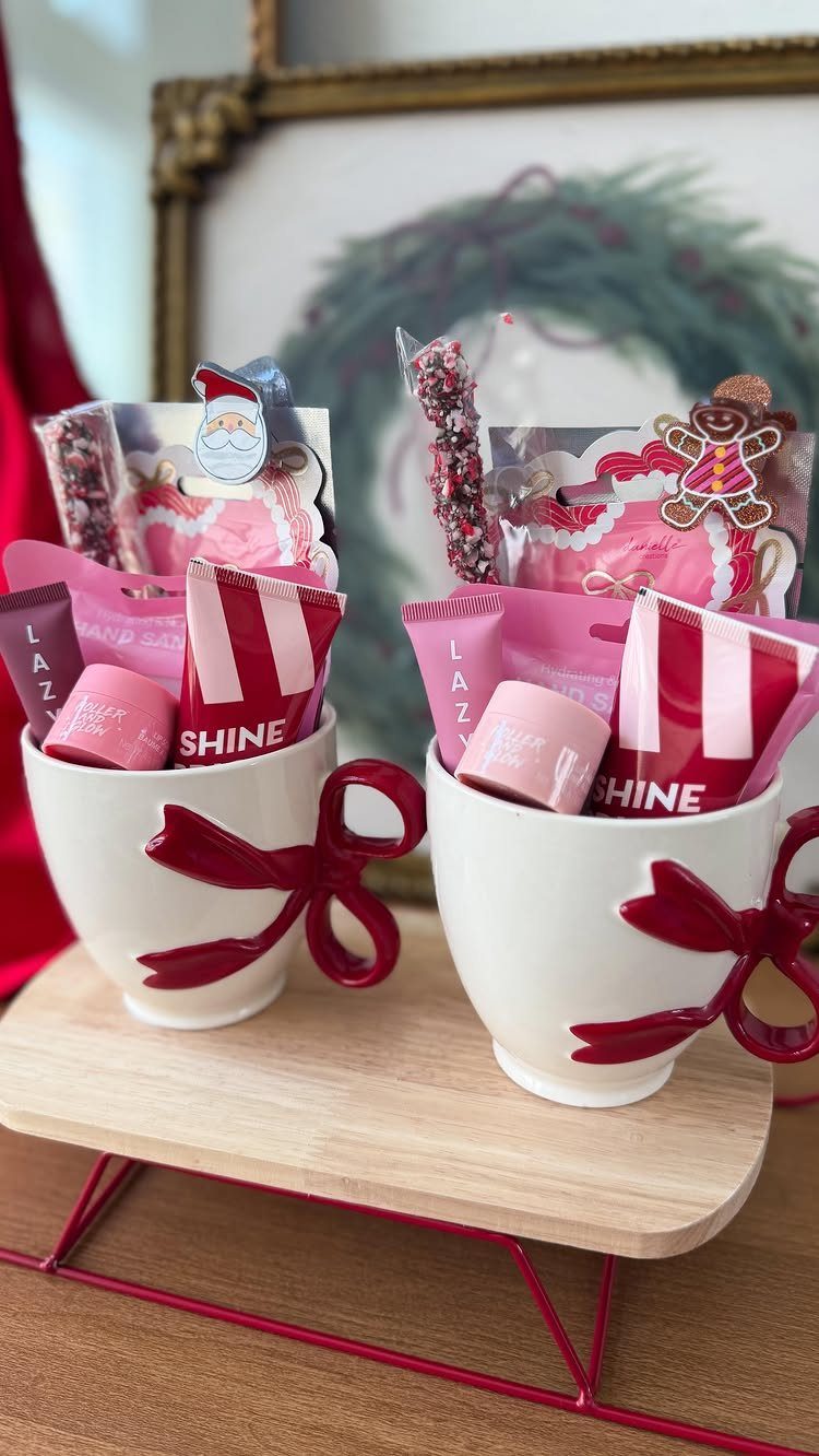 Two white mugs with red bows filled with festive pink and red treats.