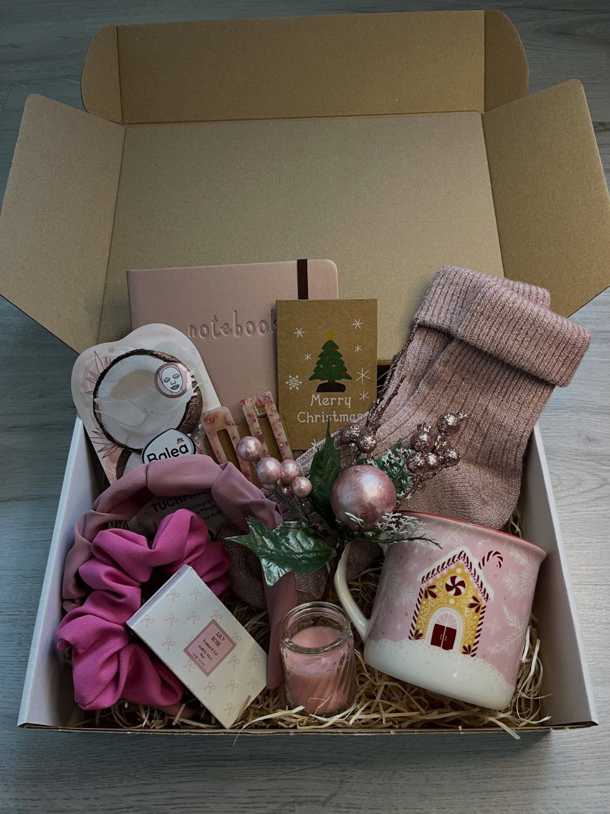 Gift box with pink socks, mug, and accessories for a Christmas care package