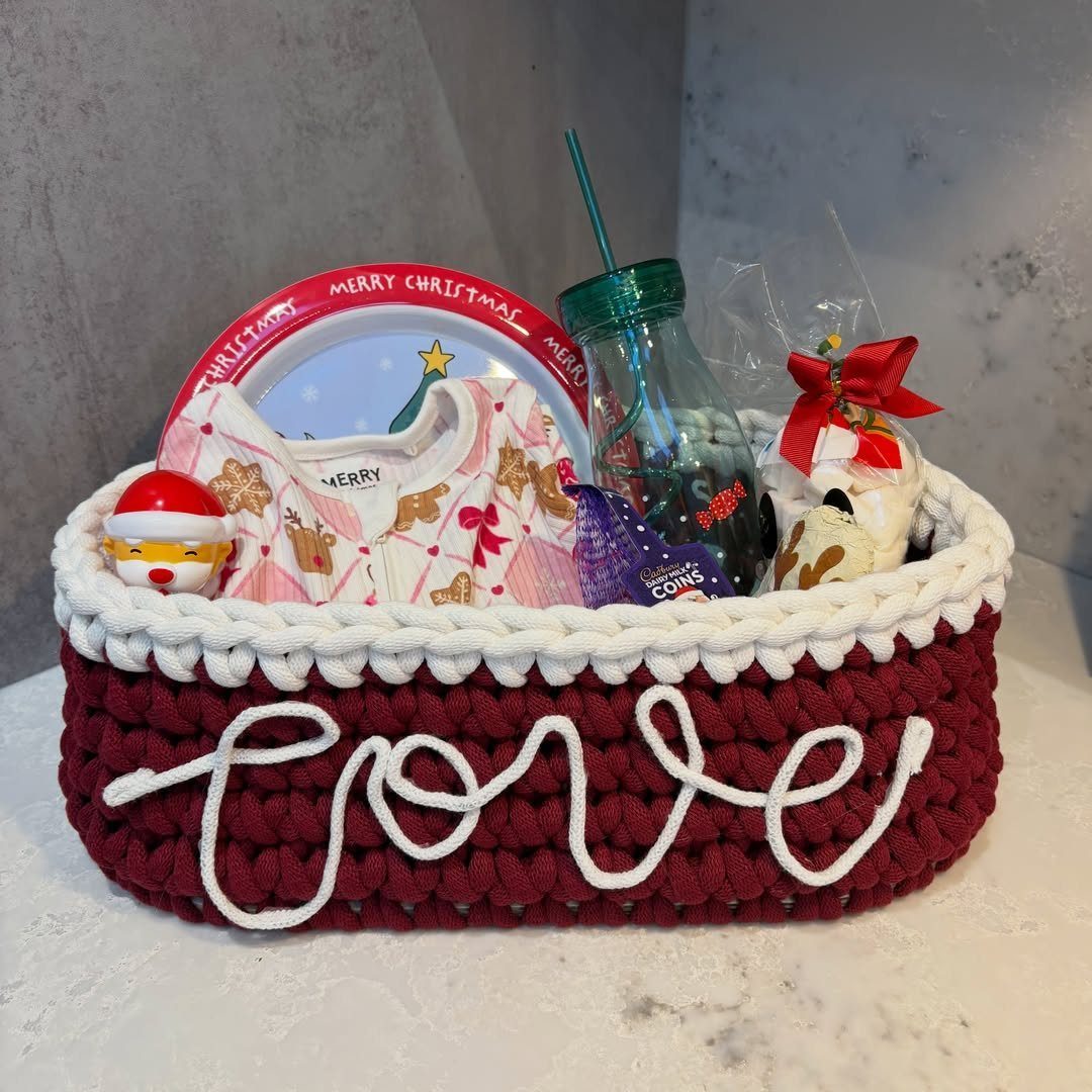 Crocheted red and white Christmas basket filled with pajamas, treats, and a plate.