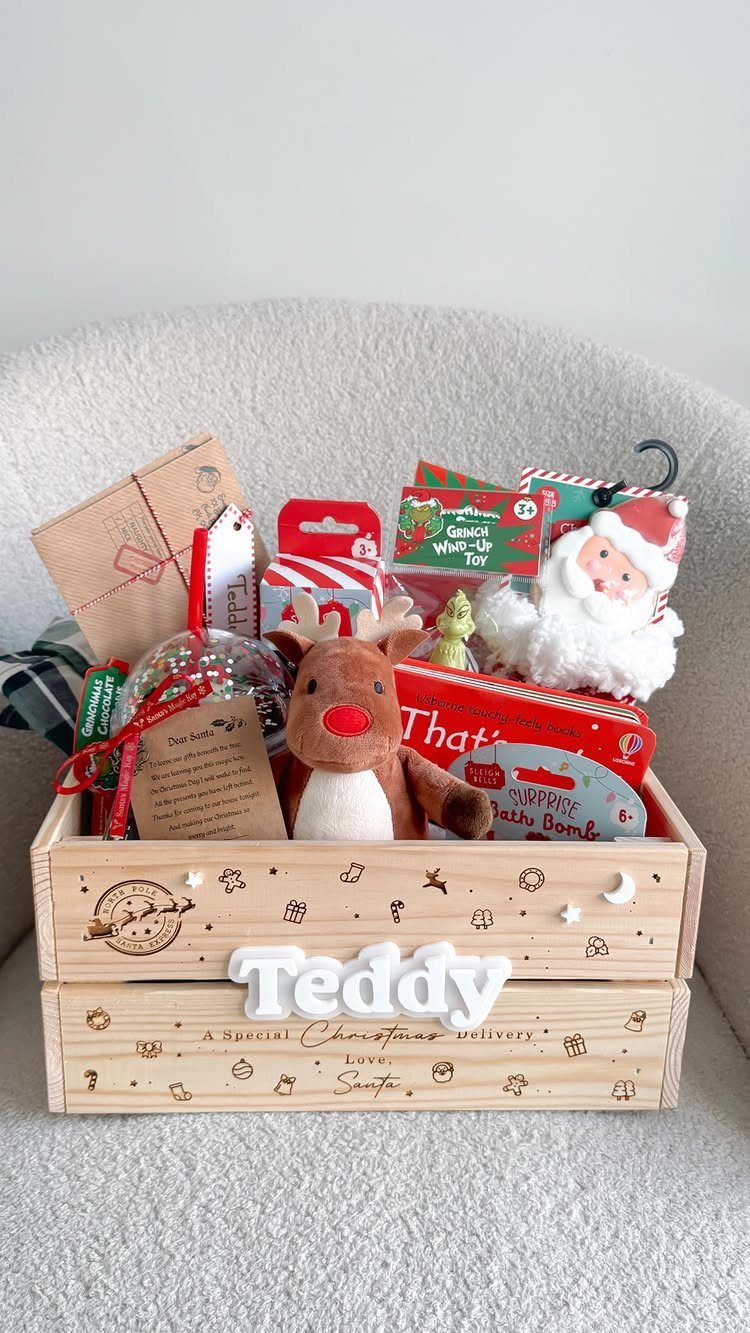 Wooden Christmas gift crate filled with toys, plush reindeer, and festive treats.