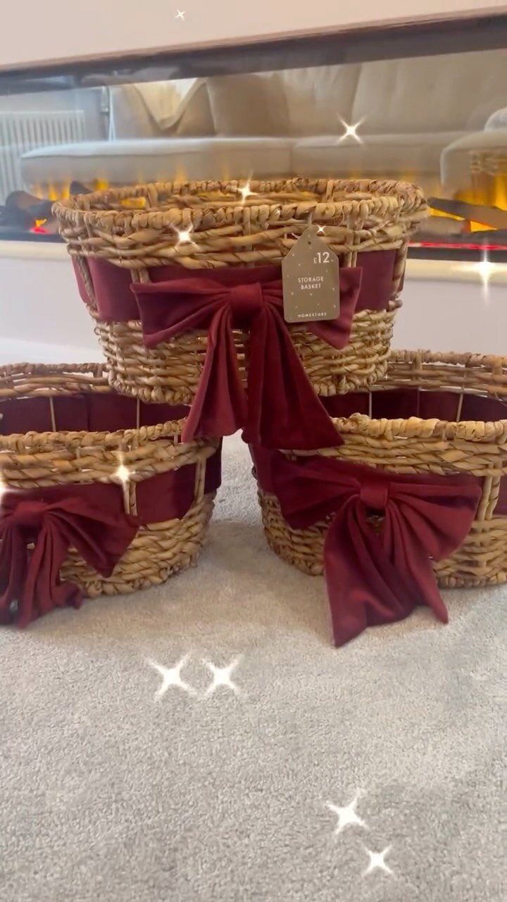 Three woven wicker baskets with burgundy velvet bows on a grey carpet.