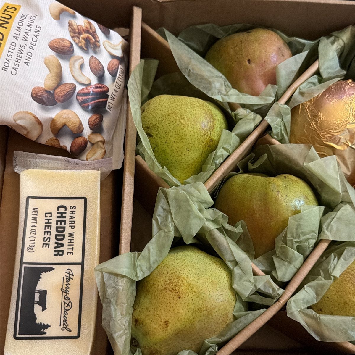 Gift box with green pears, roasted nuts, and sharp white cheddar cheese.