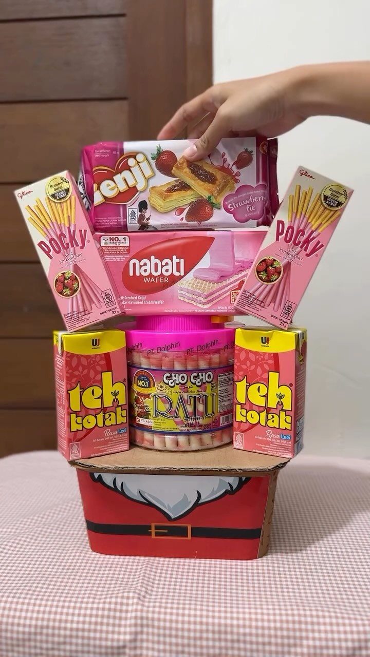 Christmas gift basket filled with pink and yellow snacks in a Santa box.