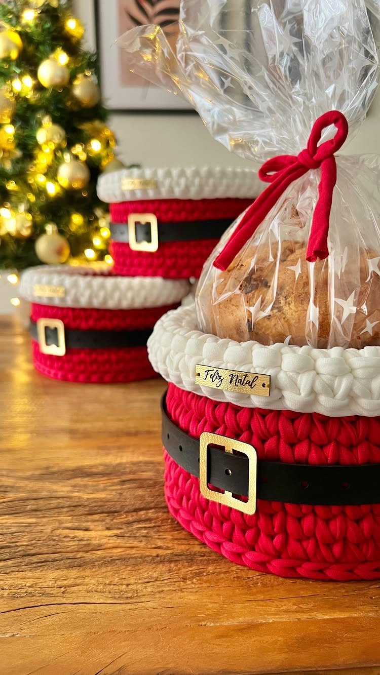 Santa hat crocheted gift baskets with a wrapped treat on a wooden table