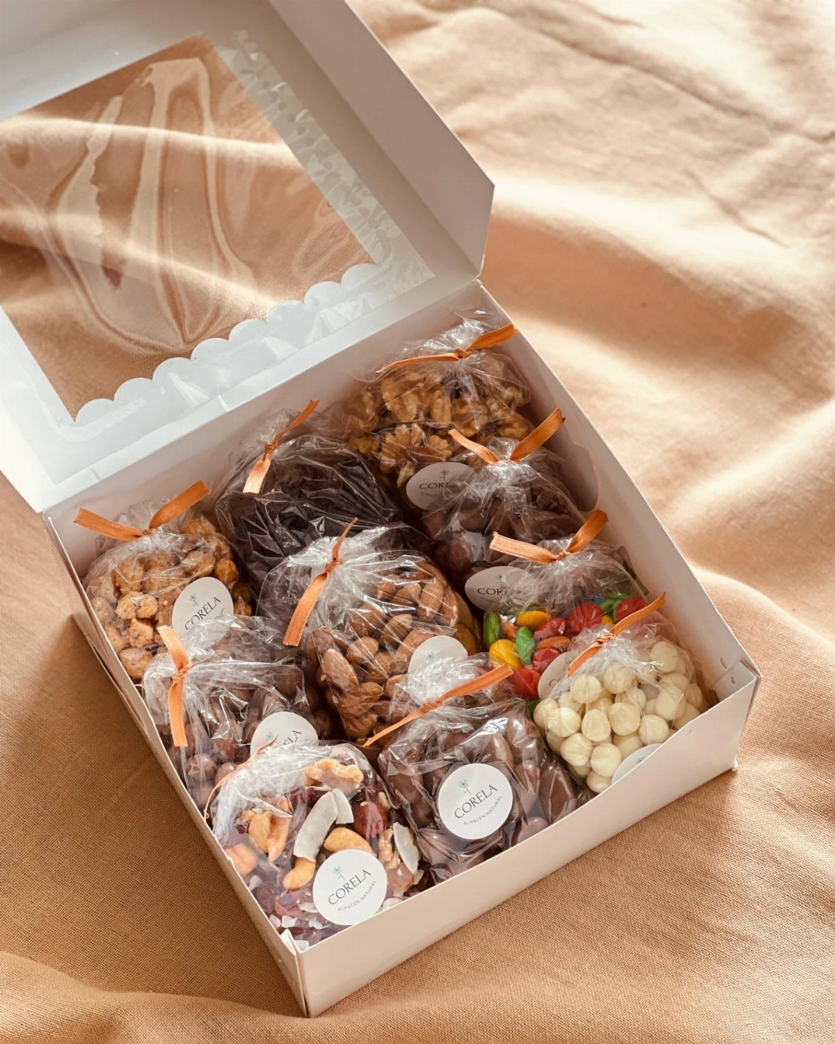 White gift box filled with small bags of assorted nuts and treats.