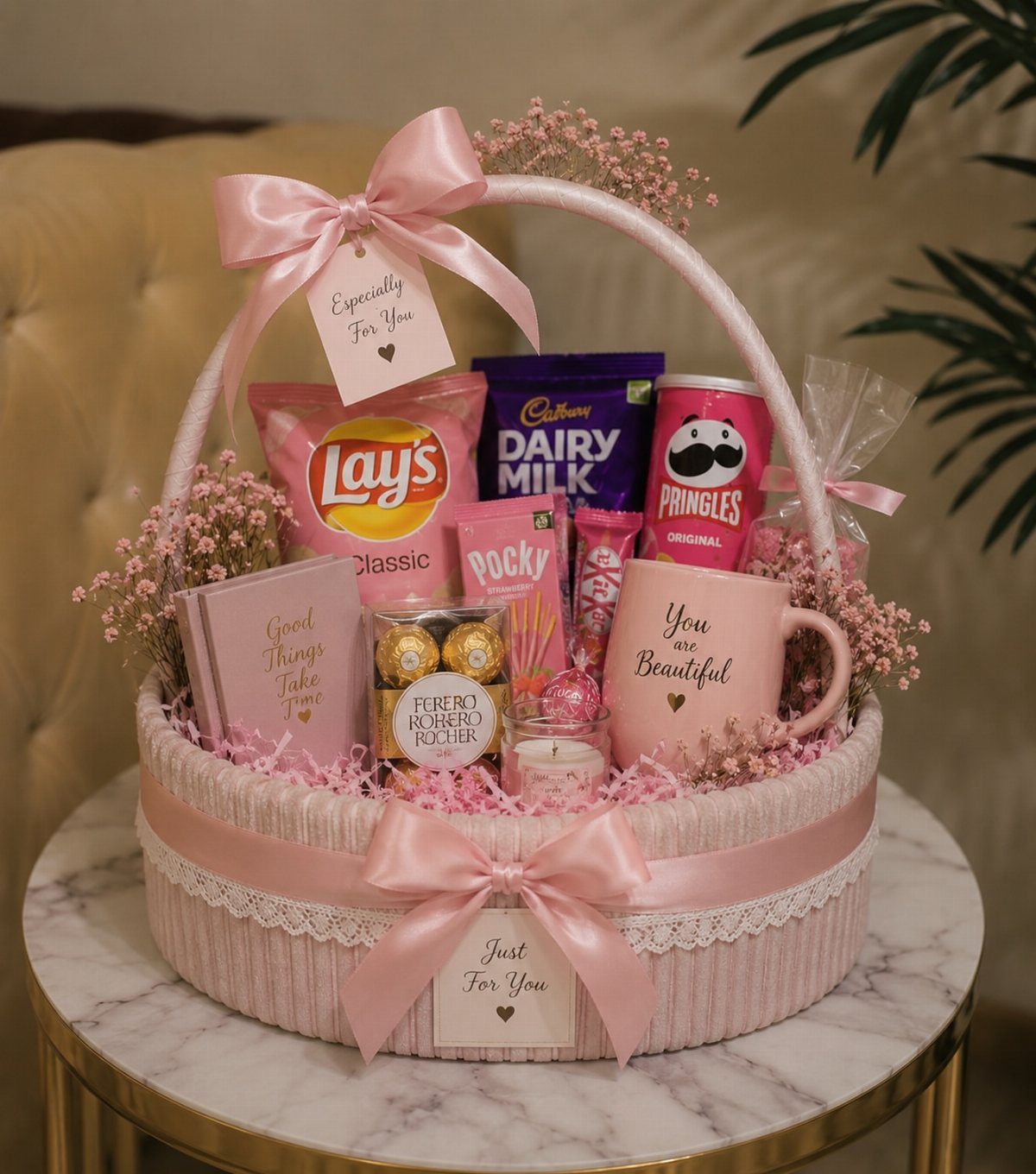 Pink gift basket with snacks, chocolate, and a mug decorated with pink ribbons.